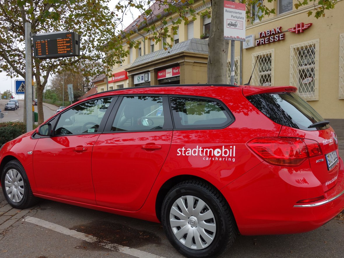 rotes Fahrzeug von Stadtmobil vor dem Asperger Bahnhof